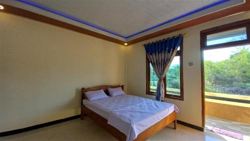 una camera con un letto di fronte a una finestra di Benedict Guesthouse by Mori Hospitality a Labuan Bajo