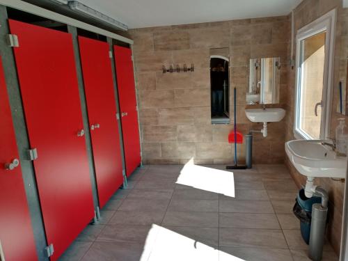 La salle de bains est pourvue de portes coulissantes rouges et d'un lavabo. dans l'établissement Insolites de la Tellerie, à Valdallière
