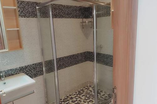 een douche met een glazen deur in de badkamer bij Appartement Costa Bouznika in Bouznika