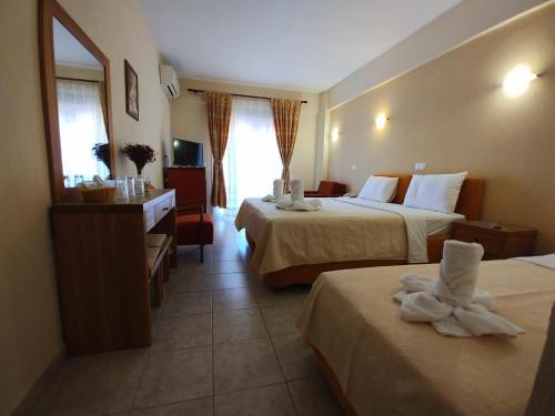 um quarto de hotel com duas camas, uma secretária e um espelho em Porto Vistonis em Lágos