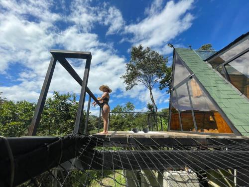 a woman in a hat standing on a bridge at Encanto Glamping in Las Dalias
