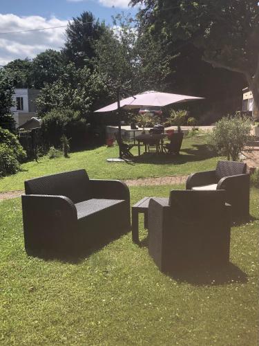3 canapés et une table de pique-nique avec un parasol dans l'établissement Charmant logement entre ville et campagne., à Montivilliers