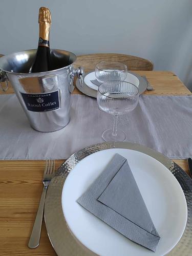a table with a white plate and a bottle of wine at Perfect Gites In Normandy in Saint-Sauveur-de-Chaulieu
