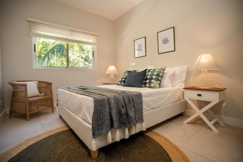 a bedroom with a bed with a nightstand and a window at Blue Coral Beachfront Penthouse in Flic-en-Flac