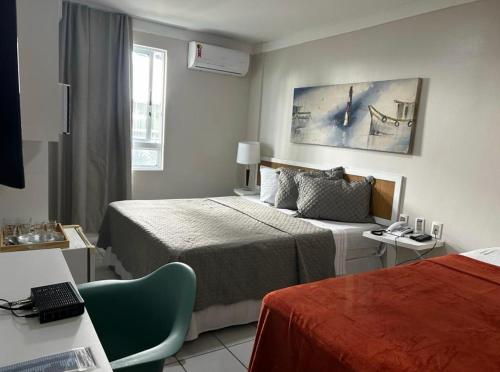 a hotel room with two beds and a chair at Ponta Negra Beach Apt 507 in Natal