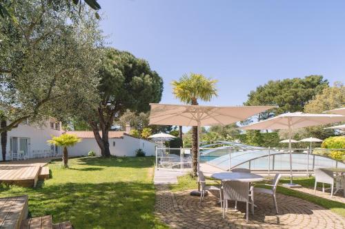 a patio with tables and umbrellas and a pool at Fleur de Sel in Noirmoutier-en-l'lle