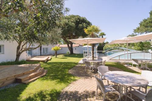 a patio with tables and chairs and a pool at Fleur de Sel in Noirmoutier-en-l'lle