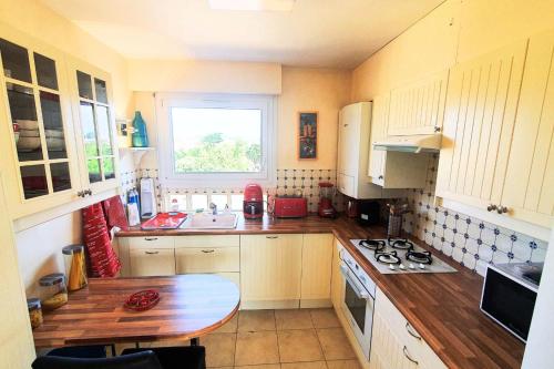 une cuisine avec des armoires blanches et une table en bois dans l'établissement Bright apt with balcony panoramic view, à Saint-Malo