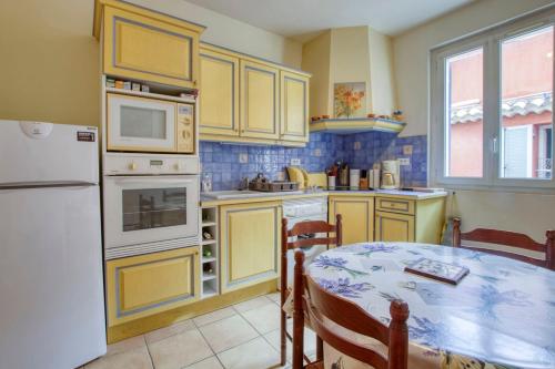 une cuisine avec une table et un réfrigérateur blanc dans l'établissement Charming apartment in the city center, à Sanary-sur-Mer