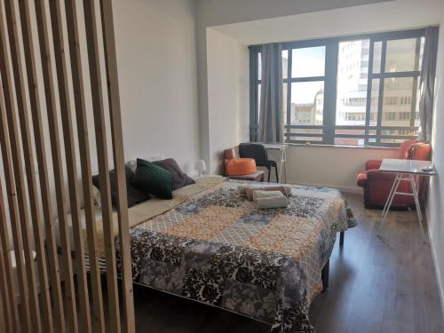 a bedroom with a bed and a couch and windows at Cais 54 Apartments in Aveiro