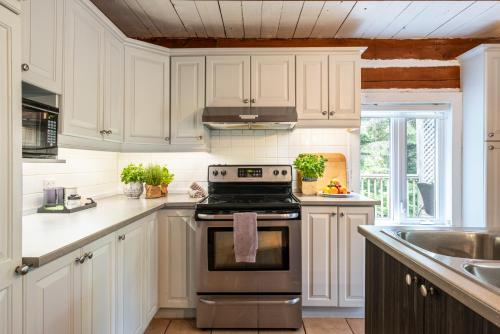 a kitchen with white cabinets and a stove top oven at Le Petit Chalet by My Tremblant Location in Mont-Blanc