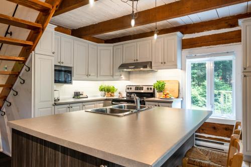 a kitchen with white cabinets and a counter top at Le Petit Chalet by My Tremblant Location in Mont-Blanc