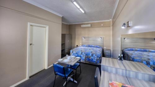 a room with two beds and a table and chairs at Comfort Inn Crystal Broken Hill in Broken Hill