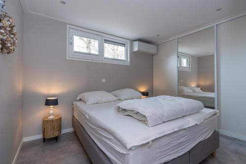 a bedroom with a large white bed and a mirror at Duinvilla's Schouwenduin in Burgh Haamstede