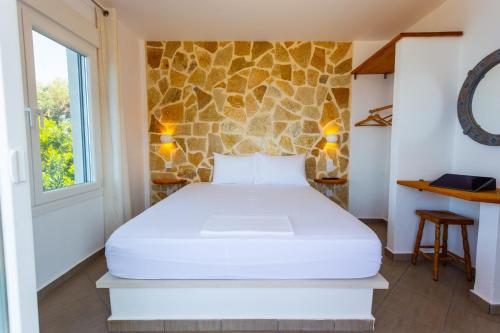 a bed in a room with a stone wall at The Life Suites in Limniónas