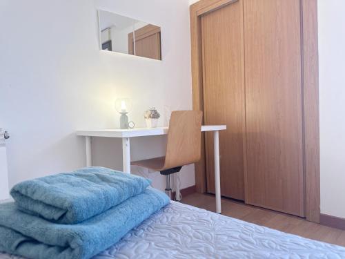 una camera da letto con scrivania e un letto con una coperta blu di Ático Universidad Salamanca (2 dormitorios) a Salamanca