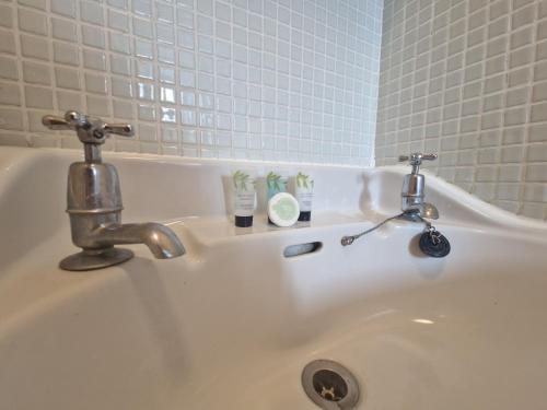 a white sink with two faucets on it at Direct Booking Prices, Studio Apartment, Free Parking, Wifi, Central, Quiet in Exeter