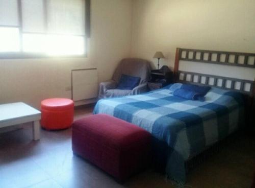 um quarto com uma cama e uma cadeira e um banco vermelho em HABITACIÓN DOBLE CON BAÑO Y ESTACIONAMIENTO-INDEPENDIENTE EN PB-NO ACEPTA ÚLTIMA HORA-dentro de casa de familia en Barrio Privado--no se aloja huéspedes de Mendoza o Solos-FINDES LARGOS RESERVA MÍNIMA 2 DÍAS- em Maipú