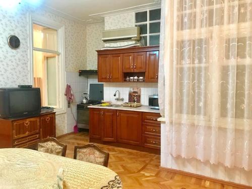 a kitchen with wooden cabinets and a table and a television at Cozy, large apartment in the heart of city center in Baku