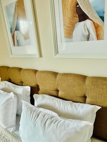 a bed with white pillows and pictures on the wall at Red House Family Hotel in Ravda