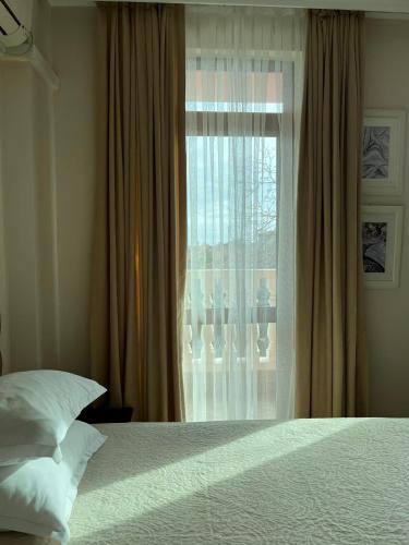 a bedroom with a bed and a window at Red House Family Hotel in Ravda