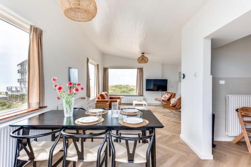 een woonkamer met een tafel en stoelen bij Zeezicht Villa Zee aan het strand in Bergen aan Zee