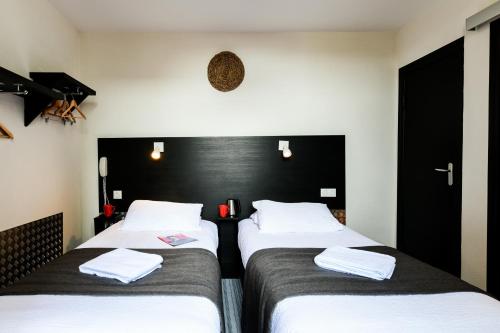two beds in a room with black and white at Hôtel Le Loft in Trie sur Baise
