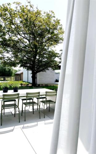 un grupo de mesas y sillas con un árbol en Fluwine en Hooglede