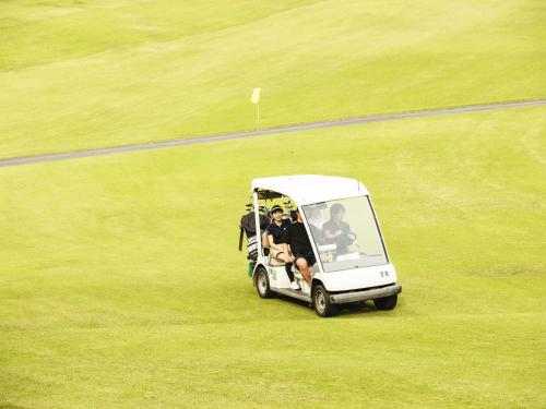 a golf cart in a field with people in it at Hole 37 in Tsukuba
