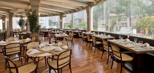 un restaurante con mesas y sillas en una habitación con ventanas en Suíte 5 estrelas Hotel Av Ibirapuera 2534 Piscina, en São Paulo