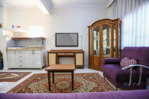sala de estar con sofá púrpura y TV en İzol Apart Evleri Adrasan, en Kumluca