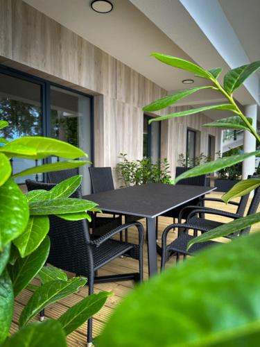 a black table and chairs on a patio with plants at Lago Apartamenty Domki in Niesulice