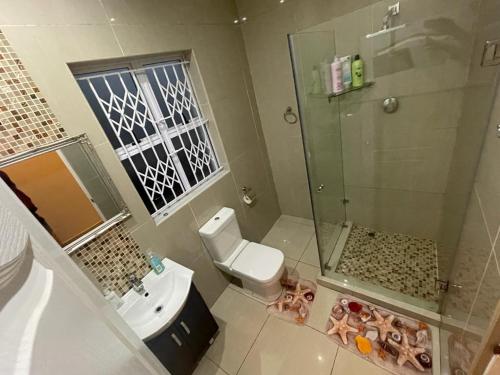a bathroom with a shower and a toilet and a sink at Illovo Beach house in Amanzimtoti