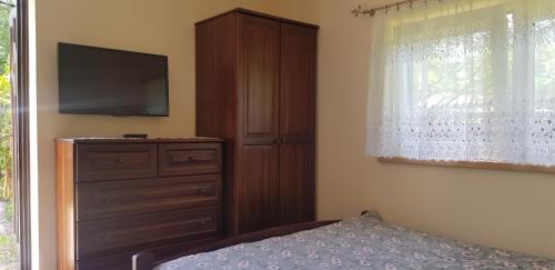 a bedroom with a bed and a dresser with a television at Gosciniec Pod Brzegiem in Ustroń