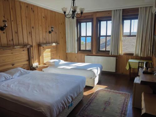two beds in a room with wooden walls and windows at Denizci Hotel in Sinop