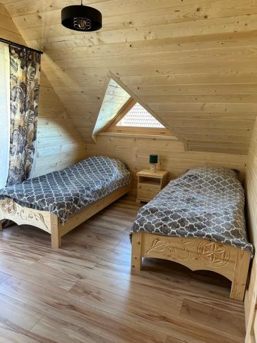 a bedroom with two beds in a log cabin at Roomflacja Bałtyk in Sianozety