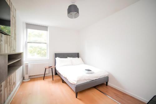 Habitación pequeña con cama y ventana en Cozy 2BR Retreat, London Rental!, en Londres