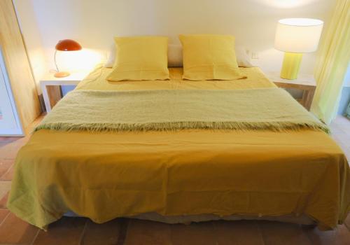 1 cama con sábanas y almohadas amarillas en una habitación en Le Mas du Lac, en Uzès