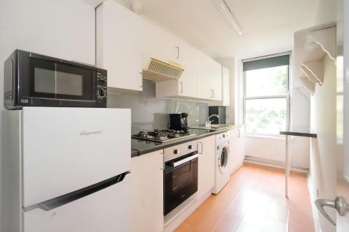 a white kitchen with a stove and a refrigerator at Cozy 2BR Retreat, London Rental! in London