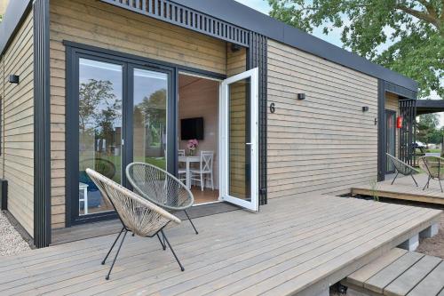 une maison dotée d'une terrasse en bois avec une chaise. dans l'établissement Black Pearl, à Dziwnów