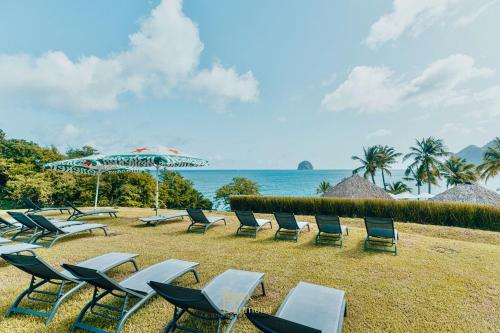 a group of chairs and umbrellas on a beach at Un petit joyau in Le Diamant