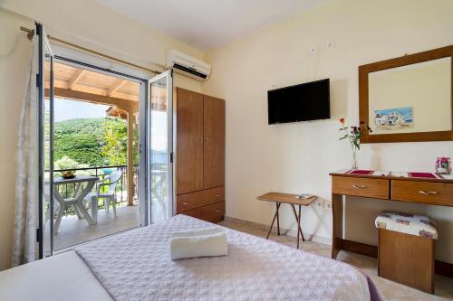 a bedroom with a bed and a television and a balcony at Vardia studio A in Mikros Gialos