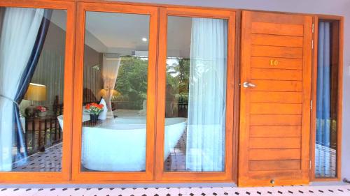 a room with glass doors and a tub in a room at Amantra homestay & village in Surat Thani