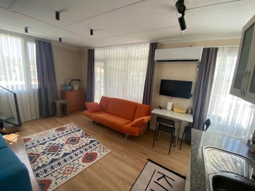 a living room with an orange couch and a desk at DENİZE 5 DAKİKA VE DOĞA EVİ in Cesme