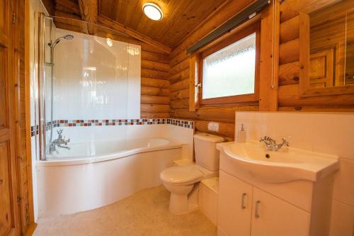 a bathroom with a tub and a toilet and a sink at Bullfinch - 2 Bed Lodge in Saxtead
