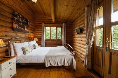 a bedroom with a bed in a log cabin at Bullfinch - 2 Bed Lodge in Saxtead