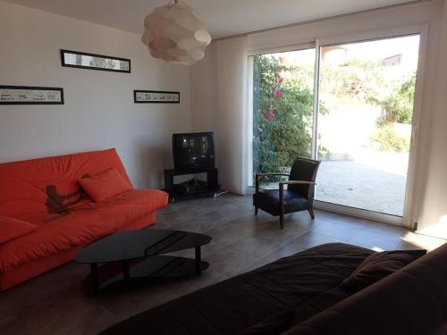 a living room with a red couch and a tv at Chez Pascal grand T2 de 55m2 indépendant dans villa in Sausset-les-Pins