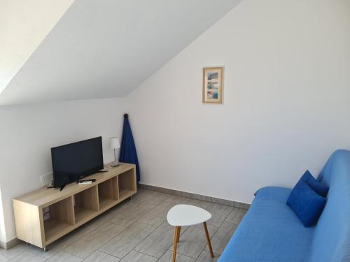 a living room with a blue couch and a tv at Apartments Toro in Sveta Nedelja