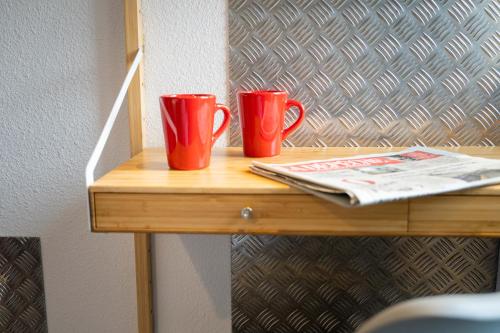 two red cups sitting on top of a wooden table at Hôtel Le Loft in Trie sur Baise