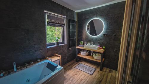 uma casa de banho com uma banheira, um lavatório e um espelho. em Chata na Skarpie - SPA i widok na Skrzyczne em Szczyrk